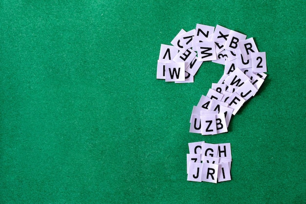 Question mark on green background with copy space made of paper with letters and numbers minimal concept of finding help answering problem analysis and learning