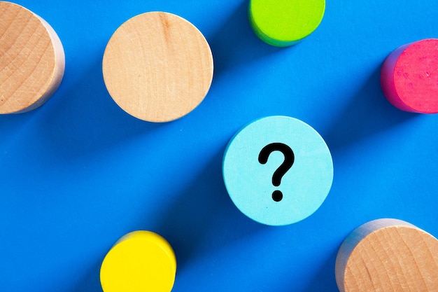 Question mark icon on blue wooden block on blue background