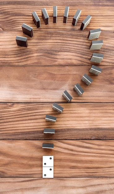 Question mark made from dominoes on the wooden table Top view