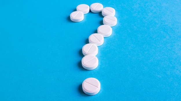 Question mark made of many white pills on a blue background. Healthcare concept. Creative medicine for health medical problem, drug interaction, medication error and pharmaceutical concept.