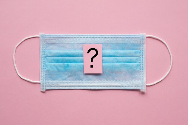 Question mark and medical bandage on a pink background. Virus protection concept