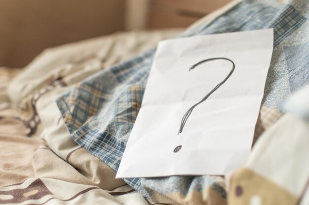 A question mark on paper on the bed