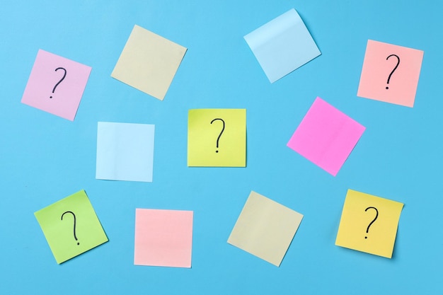 Question marks on sticky notes and colorful blank sticky notes for text space on blue background.