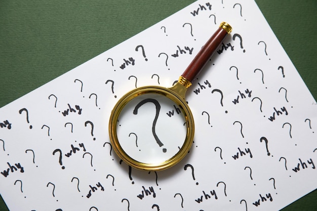 Photo question marks and why word with magnifying glass