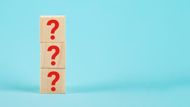 Question the shape of a wooden cube block with a question mark\
symbol on a blue background