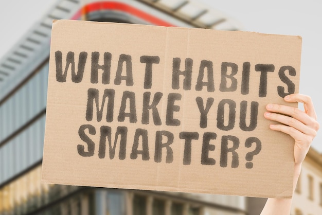 The question What habits make you smarter is on a banner in men's hands with blurred background Smart Task Wellness Smarter Productive Effect Habits Use Sad Skill Advice Tip Work