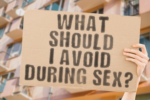 The question What should I avoid during sex is on a banner in men's hands with blurred background Intimate Prelude Distant Sensual Sexual Experience Recommendation Man Control Adult