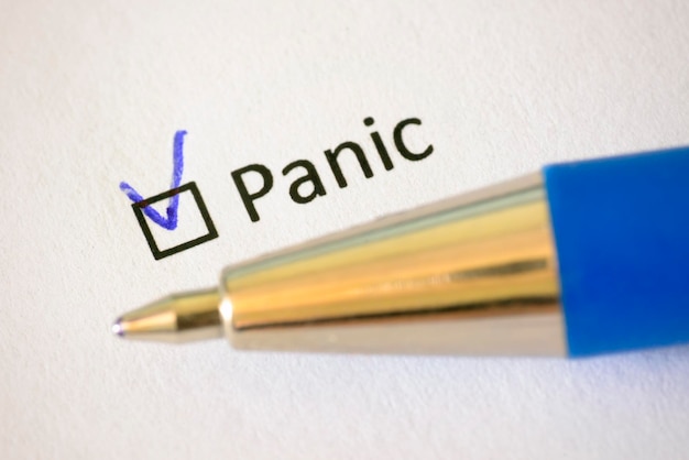 Фото Анкета синяя ручка и надпись panic с галочкой на белой бумаге