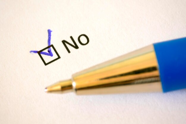 Questionnaire Blue pen and the inscription NO with check mark on the white paper