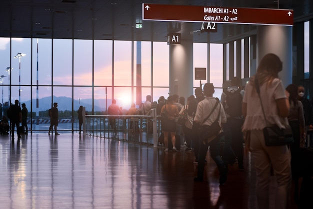 Queue of people at airport boarding gate at sunset backlight