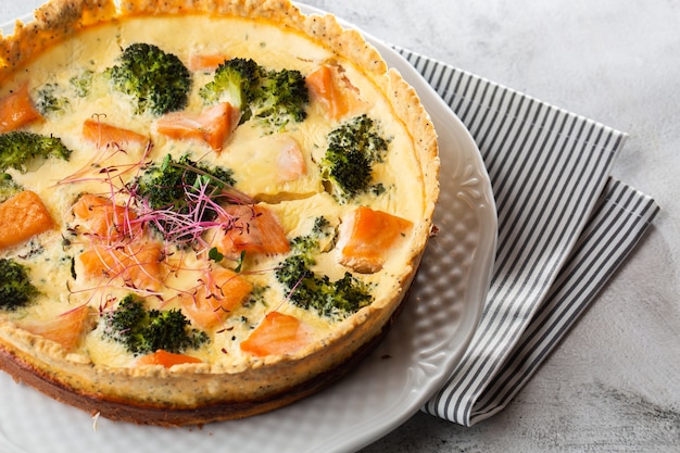 Quiche tart, top view. view from above. Classic salmon and broccoli quiche made from shortcrust pastry with broccoli florets and smoked salmon in a creamy free range egg custard close-up on the table.