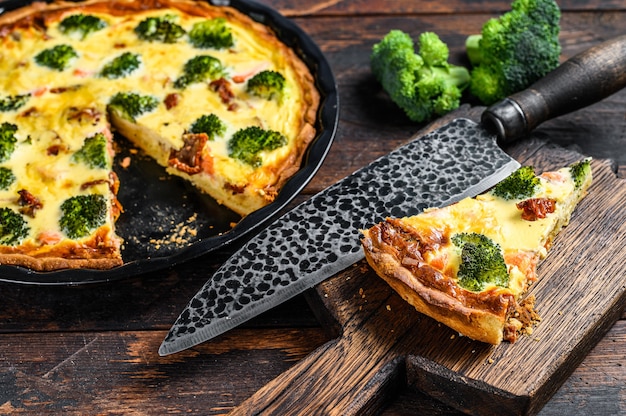 Crostata di quiche con salmone affumicato, broccoli e spinaci. fondo in legno scuro. vista dall'alto.