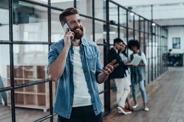 Quick business talk. Handsome young smiling man talking on the phone and gesturing 