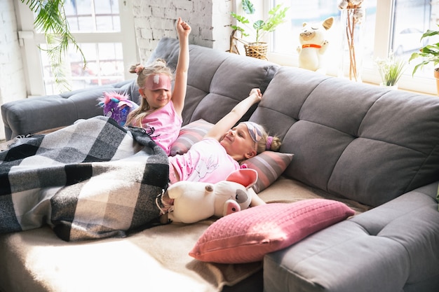 Quiet little girls playing in a bedroom in cute pajamas, home style and comfort