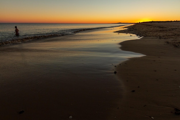 a quiet Spanish beach at sunset where people walk and run