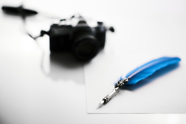 Photo quill pen and camera on white background