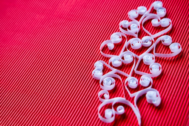 Quilling paper on red cardboard. Background with hearts for Valentine's day.