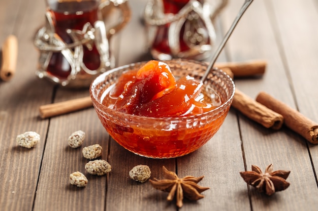 Quince jam in a glass bowl on wooden decorated table