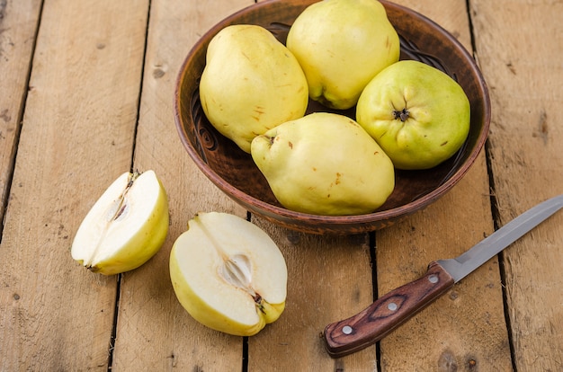 Quince in a large clay dish on a dark wooden background.