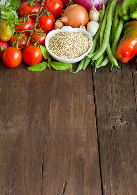 Quinoa in una ciotola e verdure fresche si chiudono su un tavolo in legno con copia spazio