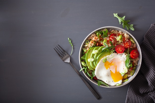 Quinoa bowl with fried egg, avocado, tomato, rocket. Healthy vegetarian lunch