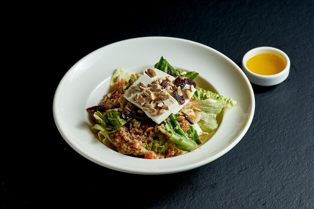 Quinoa en feta salade in witte plaat op zwarte achtergrond