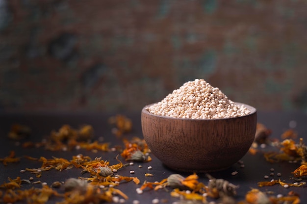 Quinoa grains in wooden bowl on black background