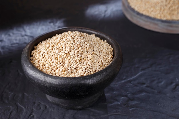 Quinoa korrels met lepel en kom op zwarte achtergrond