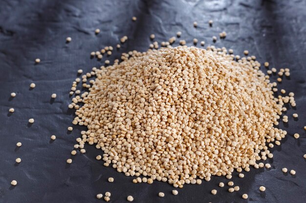 Quinoa korrels met lepel en kom op zwarte achtergrond