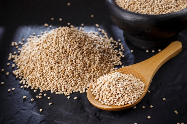 Quinoa korrels met lepel en kom op zwarte achtergrond