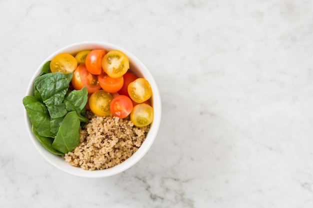 Quinoa met groenten in een kom op wit marmer