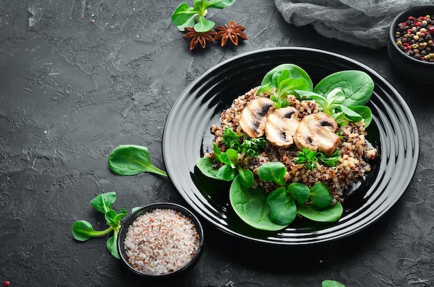 Quinoa met spinazie en champignons In een zwarte plaat op een houten achtergrond Bovenaanzicht Vrije ruimte voor uw tekst Plat leggen