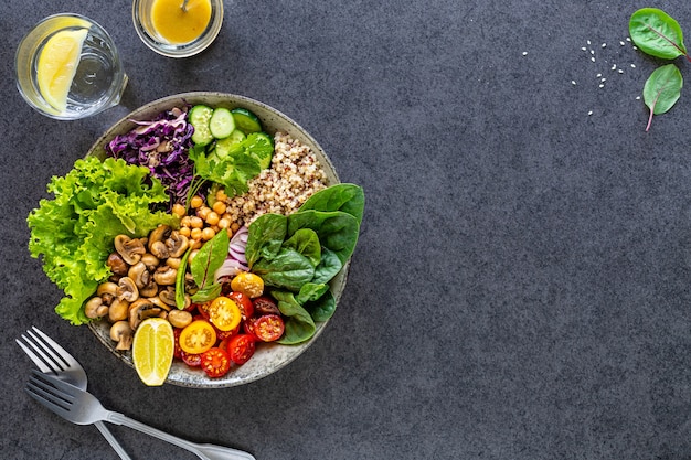 Quinoa, mushrooms, lettuce, red cabbage, spinach, cucumbers, tomatoes in a Buddha bowl