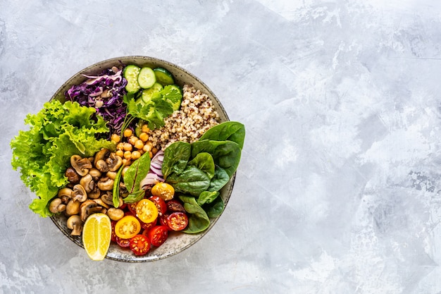 Quinoa, mushrooms, lettuce, red cabbage, spinach, cucumbers, tomatoes in a Buddha bowl