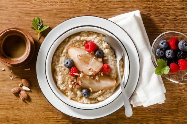 木のテーブルの上にカラメル梨と果実を入れたキノアのお粥 朝食とコーヒー