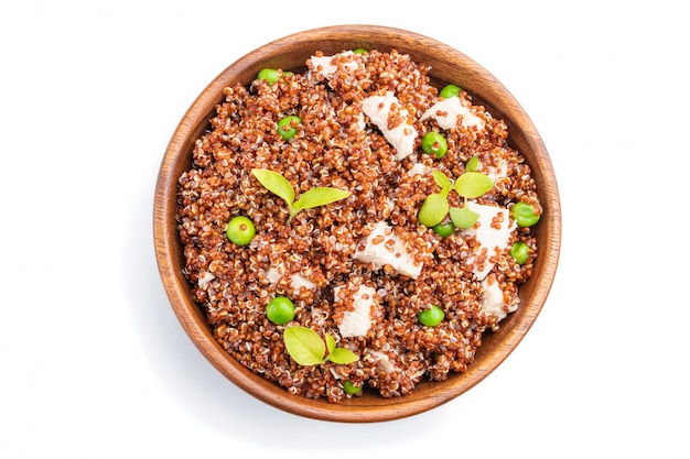 Quinoa porridge with green pea and chicken in wooden bowl isolated on a white background. Top view.