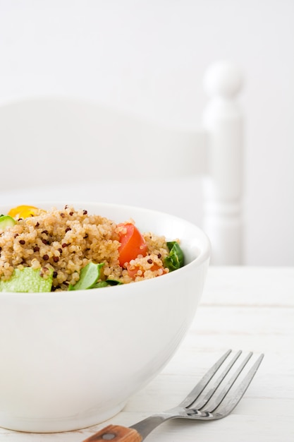 Quinoa salad in bowl on white wooden table