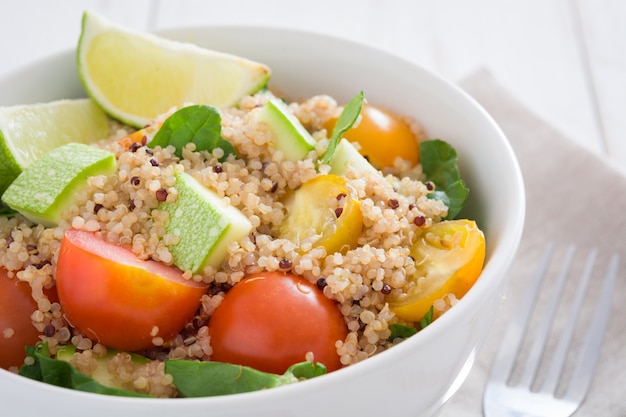 Quinoa salad in bowl with tomatoes and spinach