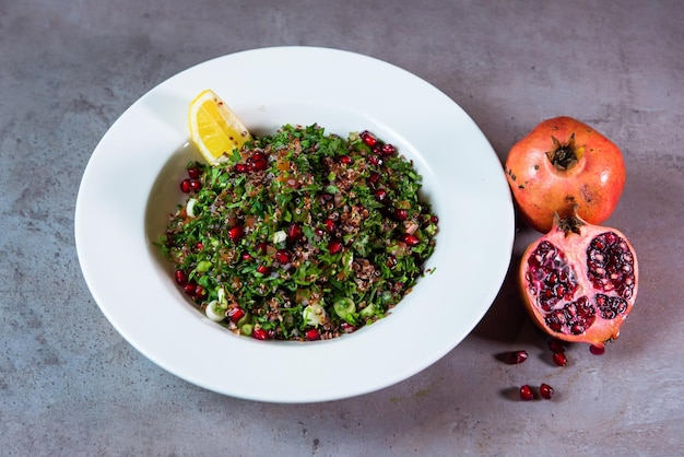 Quinoa Salad with pomegranate seeds and lime slice served in dish isolated on grey background top view of bahrain food