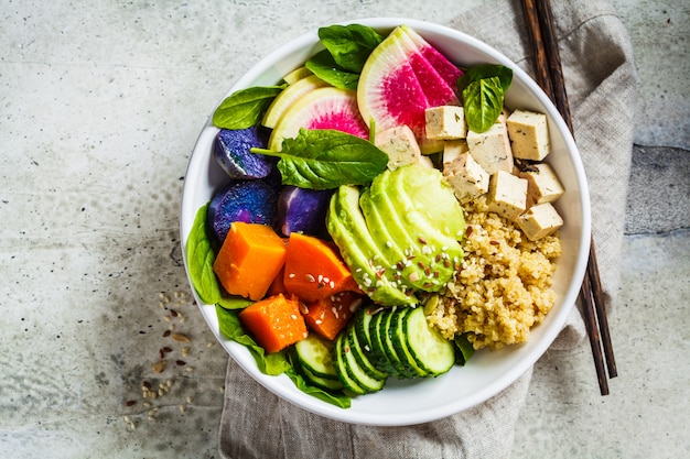 Insalata di quinoa con tofu, avocado e verdure in ciotola bianca