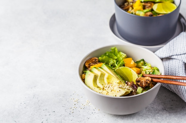 Quinoa salade met champignons, groenten en avocado's in grijze kom. gezond veganistisch eten concept.