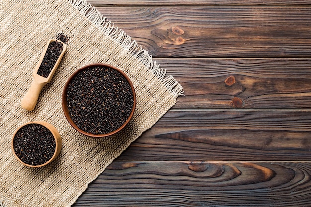 Semi di quinoa in ciotola e cucchiaio su sfondo colorato kinwa sano in una piccola ciotola superfood sano