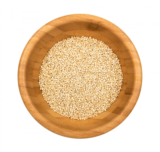 白い背景に分離された木製のボウルにキノアの種子。乾燥有機chenopodium quinoa粒のトップビュー