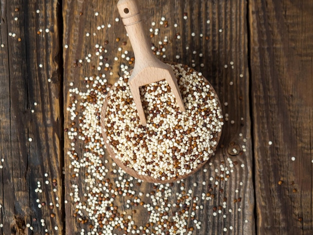 Quinoa in wooden bowl and scoop on rustic background