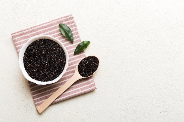 Quinoa zaden in kom en lepel op gekleurde achtergrond Gezonde kinwa in kleine kom Gezonde superfood