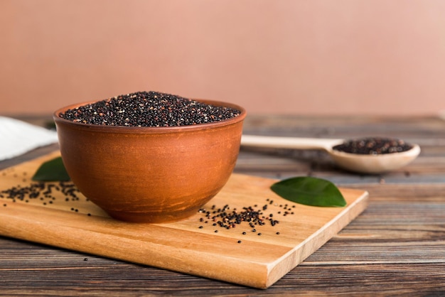 Quinoa zaden in kom en lepel op gekleurde achtergrond Gezonde kinwa in kleine kom Gezonde superfood