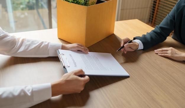 Foto esci dal lavoro uomo d'affari che invia una lettera di dimissioni e imballa le cose dimettiti deprimere o portare una scatola di cartone per affari in ufficio cambio di lavoro o licenziamento dall'azienda