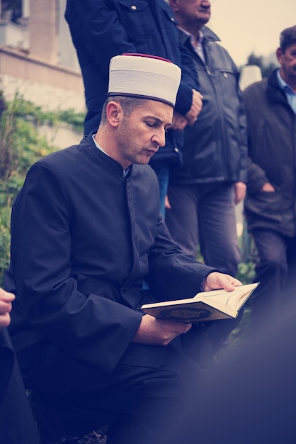 quran holy book reading by imam  on islamic funeral with white thumb stones graweyard background