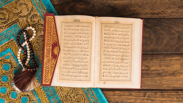 Фото Коран рядом с бусами и узорчатой ​​тряпкой