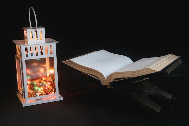 Quran open on a wooden placemat with Arabic lamp on dark background